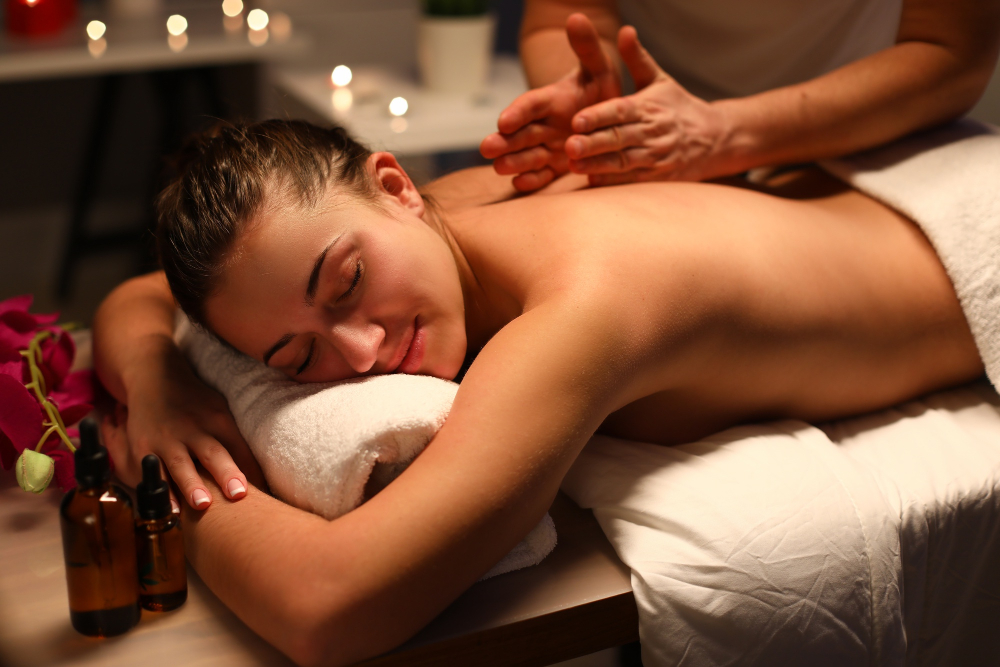 Therapist massaging a client's back with oil by candlelight